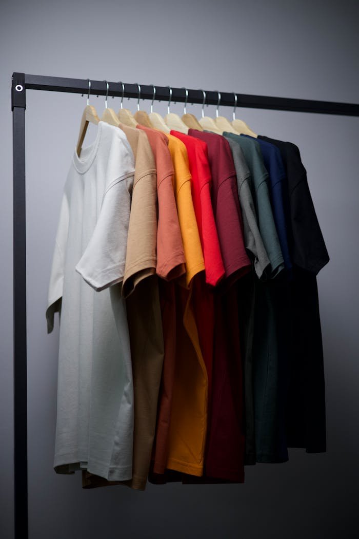 A range of colorful T-shirts neatly hung on a black clothing rack in an indoor setting.